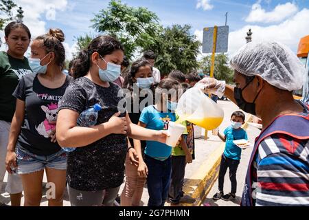 Reynosa, Messico. 15 luglio 2021. I migranti senzatetto si allineano per il succo e il cibo. Centinaia di persone hanno formato linee a seconda del sesso e dell'età, dando priorità alle donne e ai bambini. Credit: Lexie Harrison-Cripps/Alamy Live News Foto Stock