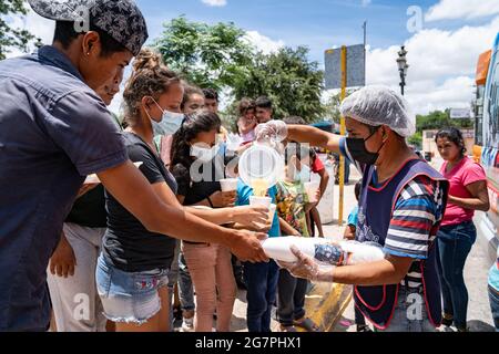 Reynosa, Messico. 15 luglio 2021. I migranti senzatetto si allineano per il succo e il cibo. Centinaia di persone hanno formato linee a seconda del sesso e dell'età, dando priorità alle donne e ai bambini. Credit: Lexie Harrison-Cripps/Alamy Live News Foto Stock