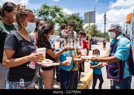 Reynosa, Messico. 15 luglio 2021. I migranti senzatetto si allineano per il succo e il cibo. Centinaia di persone hanno formato linee a seconda del sesso e dell'età, dando priorità alle donne e ai bambini. Credit: Lexie Harrison-Cripps/Alamy Live News Foto Stock