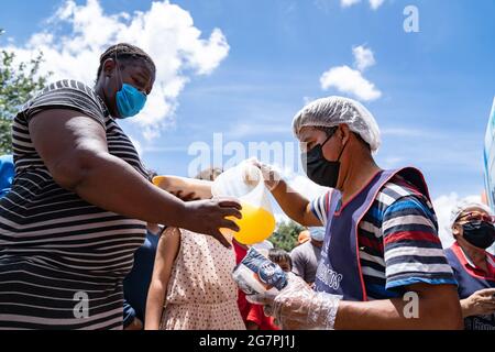 Reynosa, Messico. 15 luglio 2021. I migranti senzatetto si allineano per il succo e il cibo. Centinaia di persone hanno formato linee a seconda del sesso e dell'età, dando priorità alle donne e ai bambini. Credit: Lexie Harrison-Cripps/Alamy Live News Foto Stock