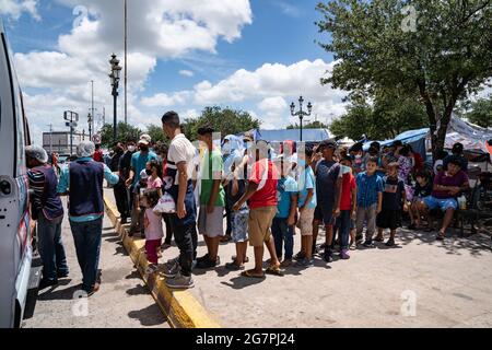 Reynosa, Messico. 15 luglio 2021. I bambini formano una fila per aspettare il cibo da un camion. Centinaia di migranti vivono sconnessi nella piazza accanto al ponte dei migranti. Credit: Lexie Harrison-Cripps/Alamy Live News Foto Stock