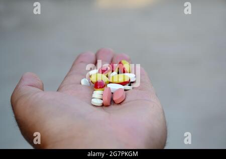 Closeup di compresse e capsule di piccole dimensioni di colore rosa, bianco con rosso, giallo Foto Stock