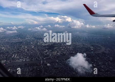 alata rossa in cielo blu scuro graduato con vista della grande città sotto sotto al sole Foto Stock