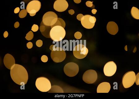 molti bokeh provenienti dai tubi delle lampadine di una strada di notte sembrano luci dorate di lusso su uno sfondo scuro Foto Stock