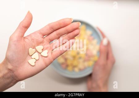 Colazione sana al mattino: Mano della donna che tiene gustosi fiocchi sulla ciotola con cereali nel braccio femminile Foto Stock