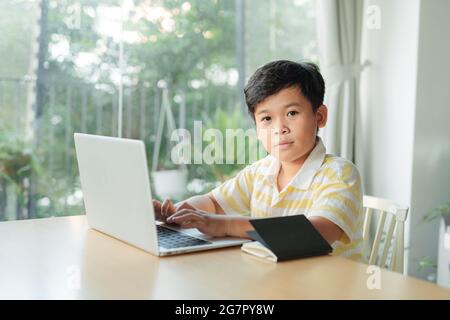 Smart Little Boy utilizza il laptop per videochiamare con il suo insegnante. Foto Stock