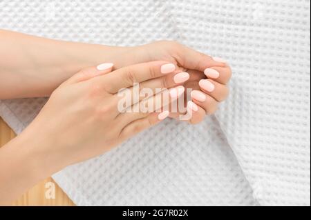 Donna bella cura delle unghie. Perfetta unghie artificiali della giovane donna. Unghie curate e mani morbide mano su asciugamano. Trattamento di bellezza. Top vie Foto Stock