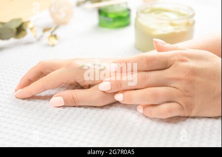 Cura della pelle delle mani. Closeup di belle mani femminili con unghie naturali Manicure. Primo piano della mano della donna che applica la crema idratante sul suo morbido seta Foto Stock