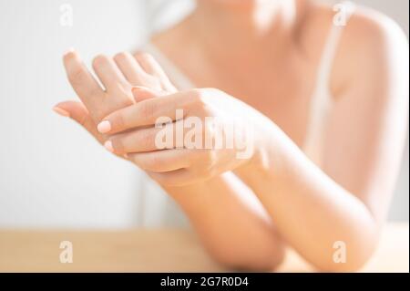 Sfoggia un'elegante posa femminile. Closeup di belle mani femminili con unghie naturali Manicure. Primo piano della mano di Donna che tocca la sua morbida guarigione seta Foto Stock