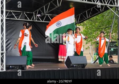 Una famiglia indiana sul palco, vestita con i loro colori nazionali e sventolando la bandiera indiana Foto Stock