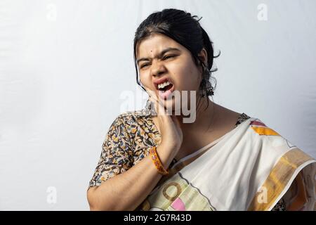 Isolato su sfondo bianco una femmina indiana in saree di fronte ai denti problema dolore su sfondo bianco Foto Stock