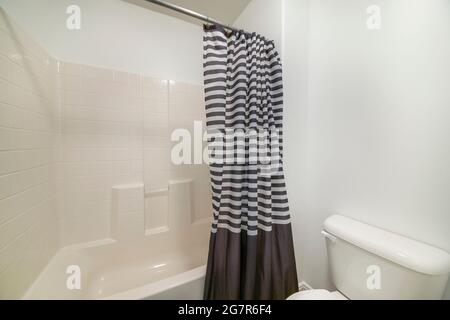 Interno bagno bianco con tenda doccia a strisce nere e bianche Foto Stock