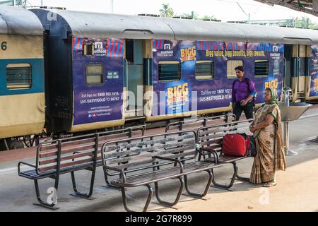 Indiane femmina che indossa sari colorati stand in attesa sulla piattaforma ferroviaria per il treno, Kerala, India Foto Stock