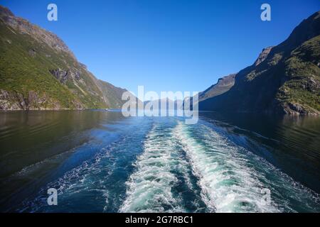 Sveglia della nave mentre si naviga scenico lungo il fiordo di Geiranger. Bellissimo paesaggio con riflessi delle montagne in acqua in una tranquilla giornata estiva, Foto Stock