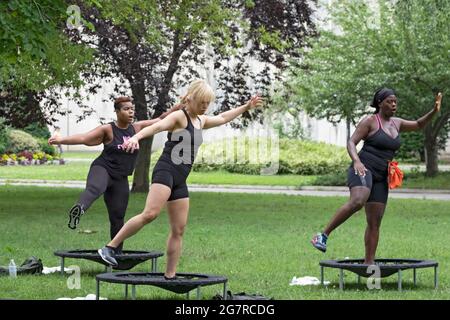 Donne che saltano dai loro trampolini durante una classe urbana di rimbalzo in un parco a Queens, New York City. Foto Stock