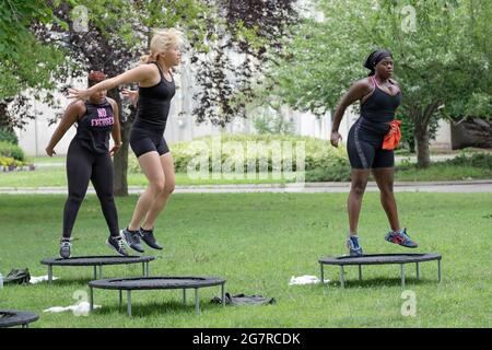 Donne che saltano dai loro trampolini durante una classe urbana di rimbalzo in un parco a Queens, New York City. Foto Stock