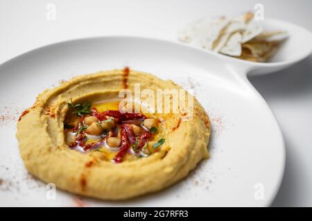 hummus con ceci, olio d'oliva, paprika e pita pane su sfondo bianco Foto Stock