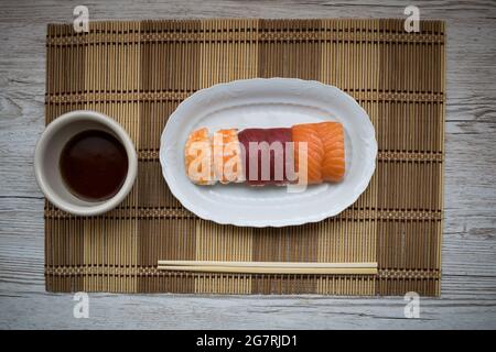 Vista dall'alto del nigiri accanto a una ciotola di soia e bastoncini Foto Stock