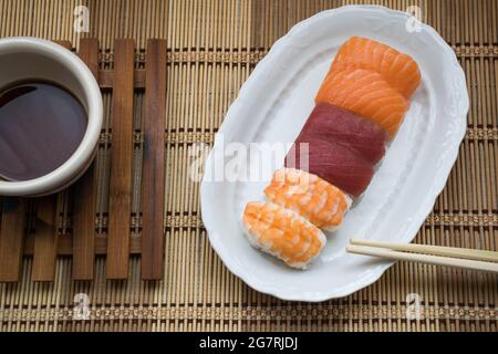 Sushi con una ciotola di soia su sfondo di legno Foto Stock