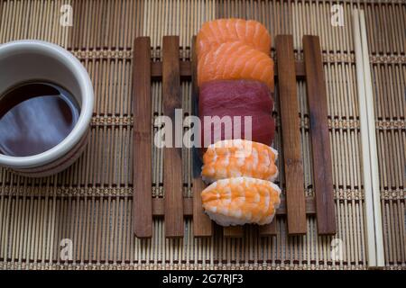 Nigiri con una ciotola di soia e bastoncini di trito su sfondo ligneo Foto Stock