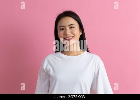 Ritratto di una donna sorridente coreana asiatica su sfondo rosa. Foto Stock
