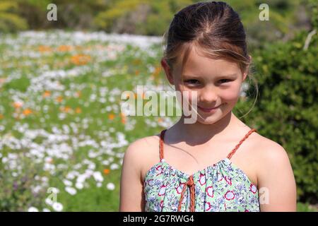 Una giovane ragazza dagli occhi blu biondo che si gode di una bella giornata di primavera e dei fiori selvatici nel West Coast National Park in Sud Africa Foto Stock