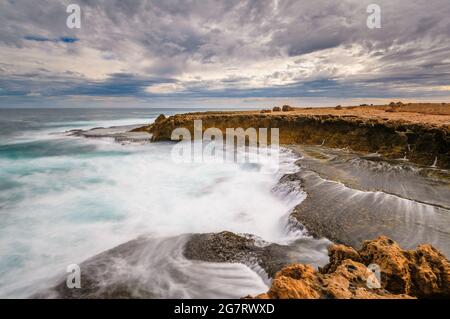 Lunga esposizione cattura delle acque ruvide sulla costa frastagliata dell'Oceano Indiano alla Stazione di Quobba nell'Australia Occidentale. Foto Stock