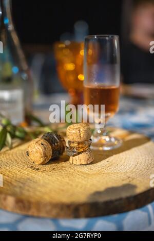 Bicchiere di champagne con due tappi rotti adagiato su tavola di legno sul tavolo Foto Stock