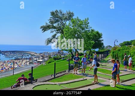 Lyme Regis, Regno Unito. 16 luglio 2021. Come l'onda di calore continua la gente sta giocando il golf pazzo sopra guardando Lyme Regis con la spiaggia piena di cercatori di sole di vacanza. Credito immagine: Robert Timoney/Alamy Live News Foto Stock