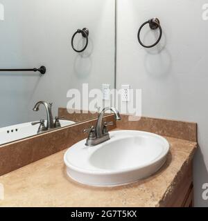 Cornice quadrata Sink con piano di granito e uno specchio all'interno di un bagno Foto Stock