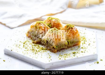 Baklava con pistacchio su sfondo bianco di legno. Baklava su pavimento in marmo Foto Stock