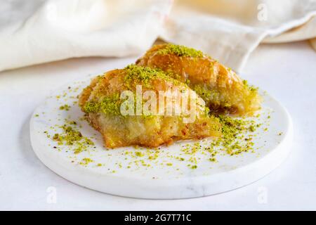 Sobiyet baklava con pistacchio su sfondo bianco di legno. Baklava su pavimento in marmo. Foto Stock