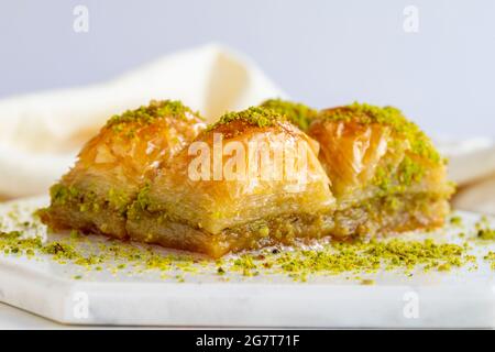 Baklava con pistacchio su sfondo bianco di legno. Baklava su pavimento in marmo Foto Stock