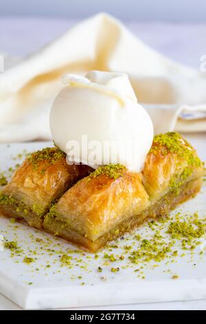 Pistacchio baklava con gelato su fondo bianco di legno. Baklava su pavimento in marmo. Gelato baklava Foto Stock