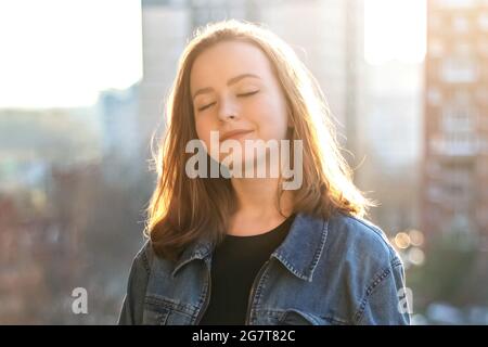 Ritratto di una giovane adolescente contro un muro di mattoni al tramonto. Foto Stock