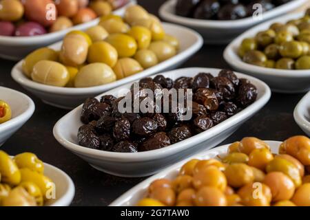 Assortimento di olive sulla piastra sfuso. Olive nere biologiche, varietà di olive Foto Stock