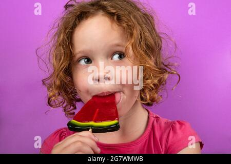 bambino godendo lollipop angelone, bambina graziosa che lecca la caramella. Foto Stock