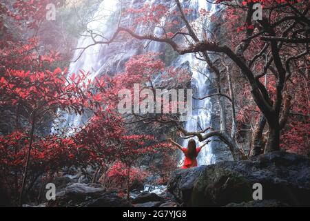 La cascata di Klong LAN è un'attrazione turistica naturale in Thailandia. C'era una giovane signora in rosso, in piedi con la schiena, alzò le mani ed era molto Foto Stock