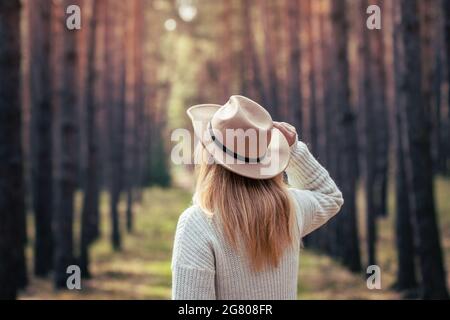 Boho donna che indossa cappello e maglia maglione in legno. La donna gode di aria fresca all'aperto nella natura Foto Stock