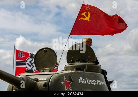 Carro armato russo che batte il martello e falce bandiera rossa. Carro armato T-34 della seconda guerra mondiale in occasione di un evento di rievocazione militare a Essex, Regno Unito. Bandiera rossa che vola Foto Stock