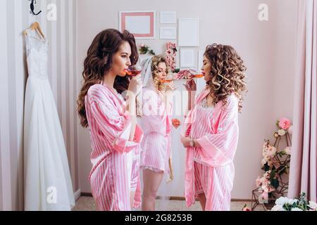 Festa di gallina. Festa per le ragazze. I girlfriends bevono champagne rosa prima della cerimonia nuziale in pigiami rosa. Foto Stock