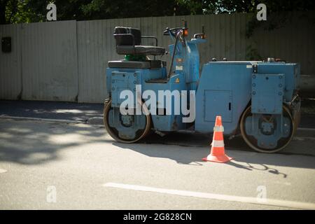 Stacker per asfalto su strada. Attrezzature da costruzione per l'arrotolamento dell'asfalto. Foto Stock