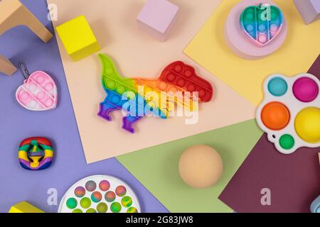 Popolari giocattoli in silicone anti-stress pop-it per un bambino su sfondo giallo viola verde-blu. Trendy reliever stress sensoriale Fidget Toy. Foto Stock