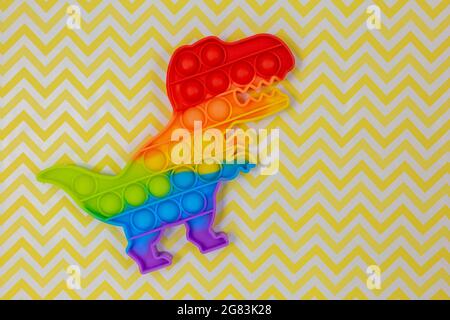 Popolari giocattoli in silicone anti-stress pop-it per un bambino su sfondo giallo. Trendy reliever stress sensoriale Fidget Toy per bambini e adulti Foto Stock