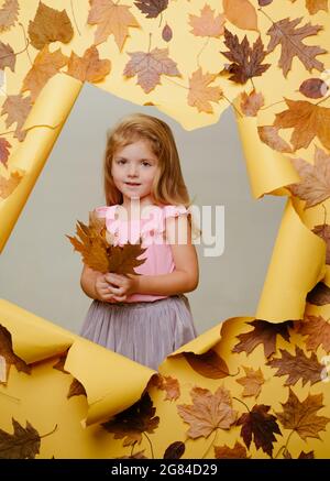 Ragazza in abito autunnale. Spazio di copia per la pubblicità. Bambini che giocano. La caduta delle foglie è un periodo bello e colorato dell'anno. Foto Stock