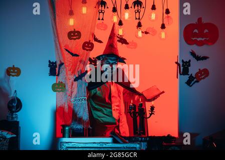 L'uomo pronuncia un incantesimo, legge un libro magico. Decorazione di Halloween e concetto spaventoso. Sfondo di Halloween. 31 ottobre. Faccia divertente. Gente pazza. Foto Stock