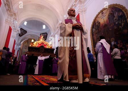 Sacerdoti cattolici vestiti con abiti viola che portano l'Anda (Float) Di Gesù che porta la croce durante Semana Santa o Santa Celebrazione settimanale all'interno della chiesa di San Francisco el Grande nel Città di Antigua Guatemala Foto Stock