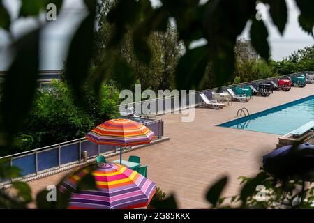 Ombrelloni colorati e sedie a sdraio vicino alla piscina. Foto Stock