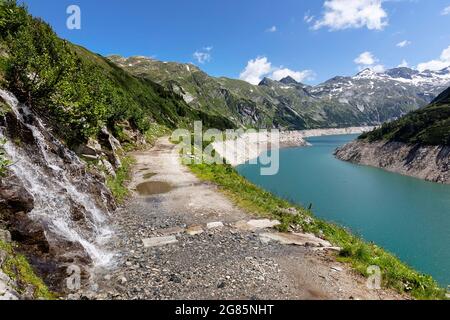 Piccola cascata vicino alla strada di ghiaia lungo il lago artificiale di Kölnbreinsperre alla fine della strada alpina di Malta, Carinzia, Austria Foto Stock