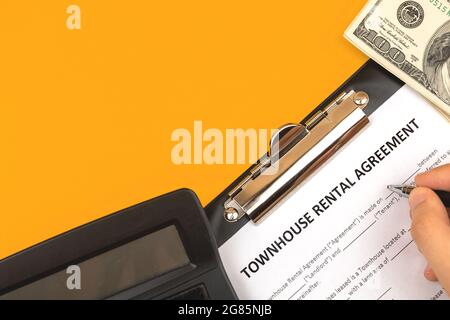 Modulo di contratto di affitto di un'abitazione di proprietà dell'uomo. Scrivania da ufficio con calcolatrice e denaro. Vista dall'alto Foto Stock